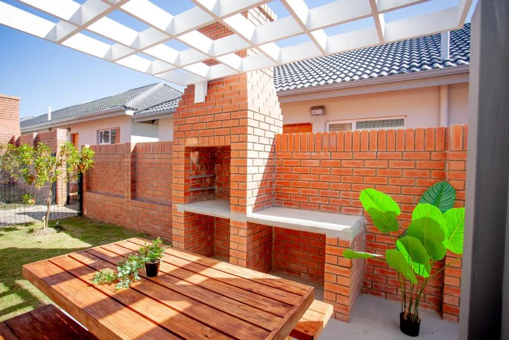Wooden deck with shade pergola, brick walls, and potted plants