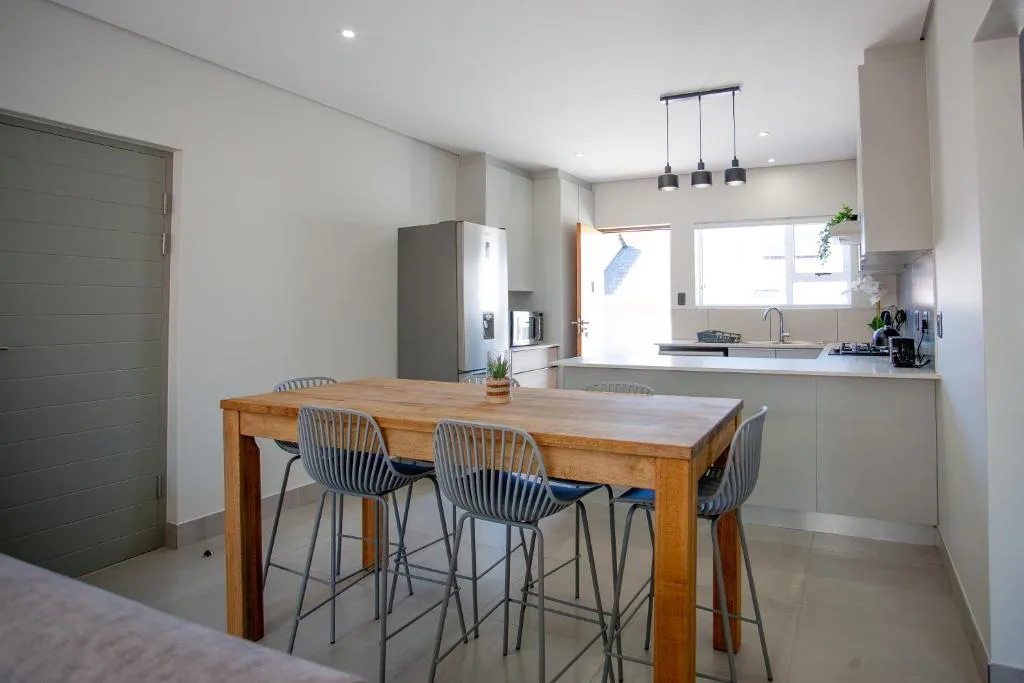Modern dining area with wooden table and bar seating overlooking kitchen
