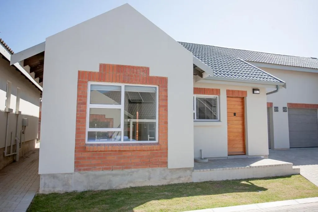 Modern white townhouse with red brick accents and orange door entrance