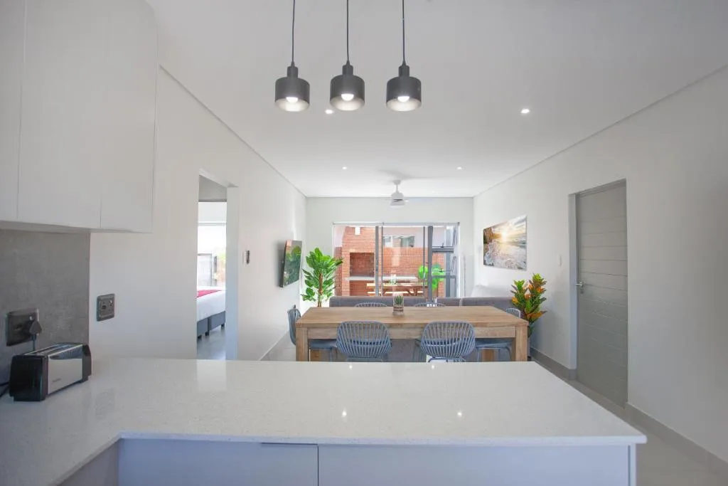 Modern open-plan kitchen with white cabinetry and pendant lighting