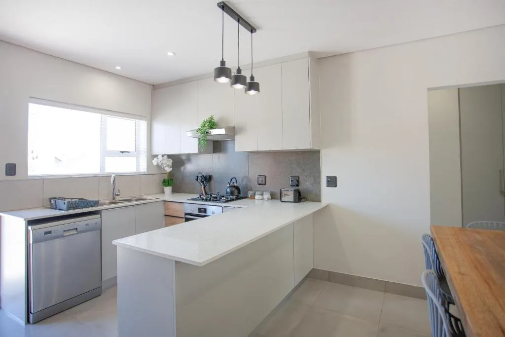 Modern white kitchen with island bench, stainless steel appliances, pendant lighting