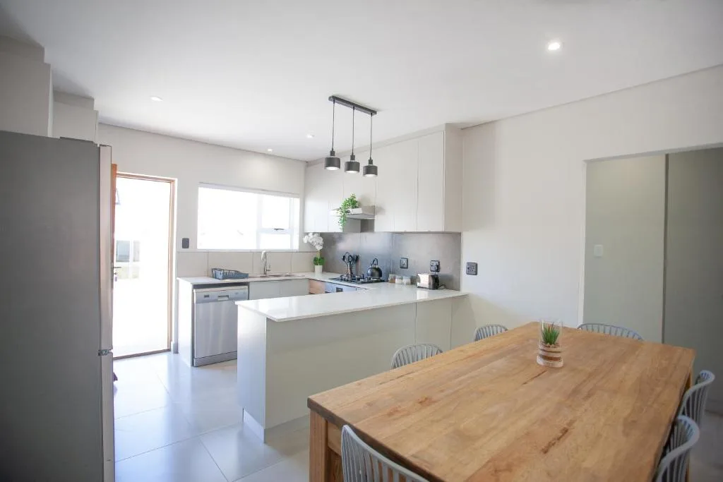 Modern open-plan kitchen with white cabinetry and dining table in foreground