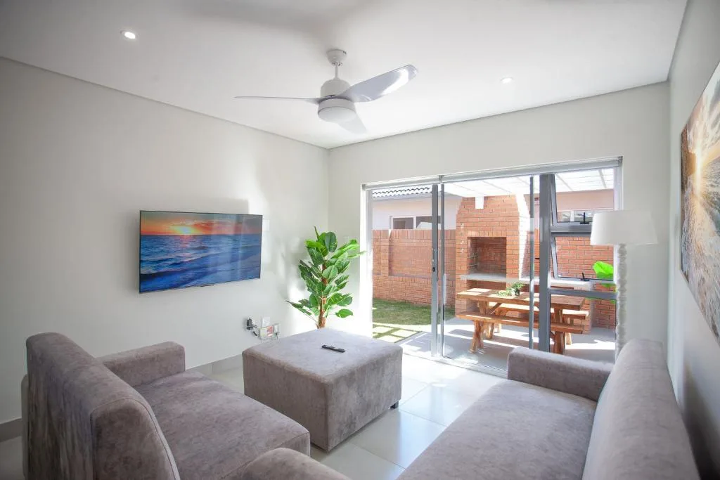 Modern lounge with gray sofas, TV, and sliding doors to outdoor patio area