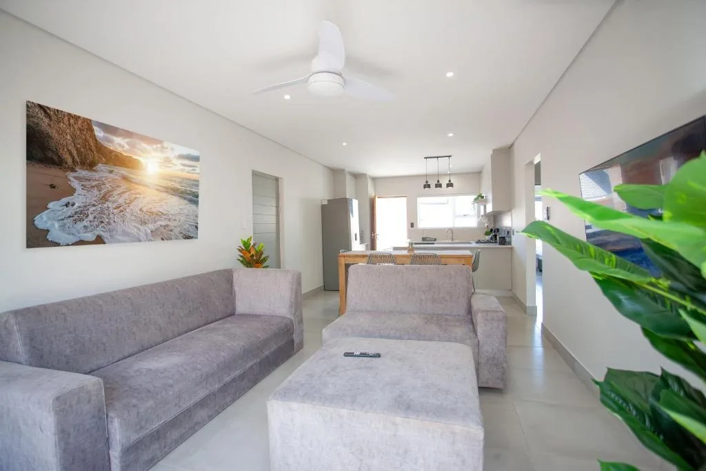 Modern open-plan lounge with gray sofas and kitchen visible beyond