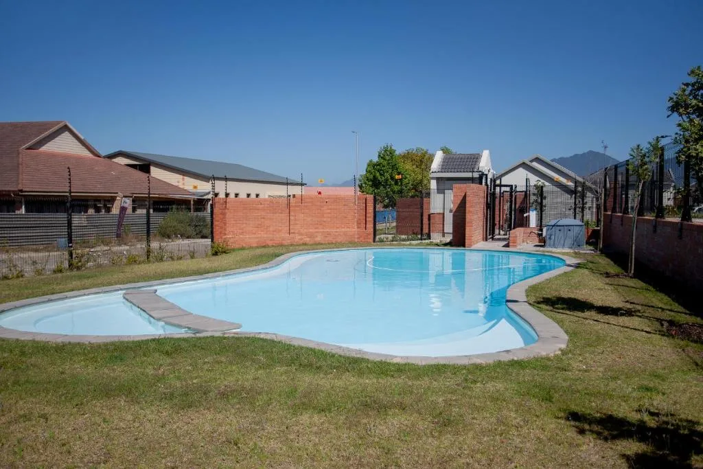 Curved swimming pool with clear blue water surrounded by manicured lawn