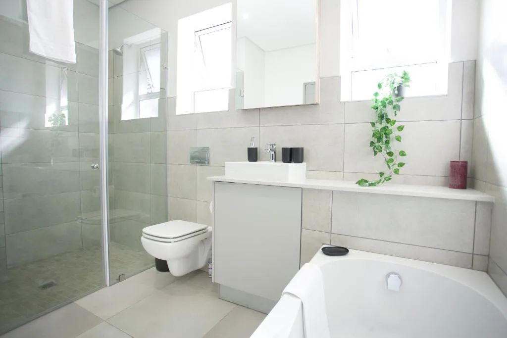 Modern bathroom with walk-in shower, toilet, bathtub, and white vanity