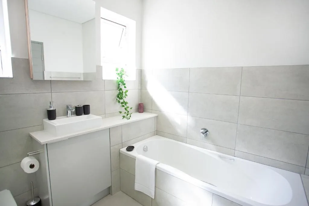 Modern bathroom with white bathtub, vanity sink, and gray tile wall accents