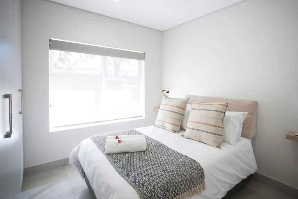 Bright bedroom with queen bed, striped pillows, and large window