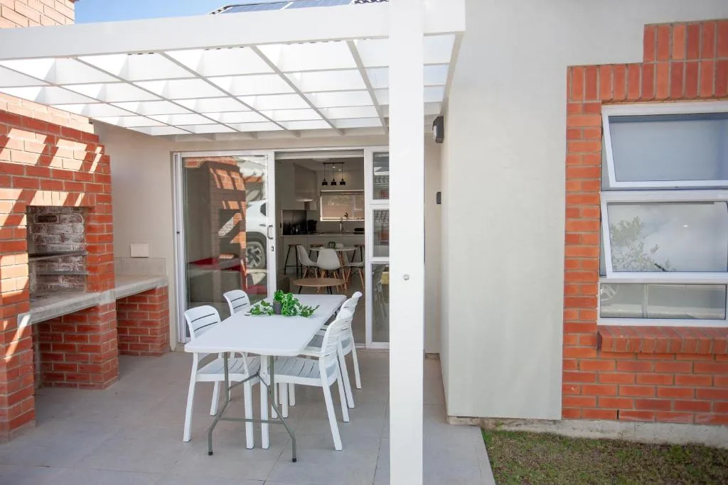 Covered patio with white dining table and chairs, modern pergola