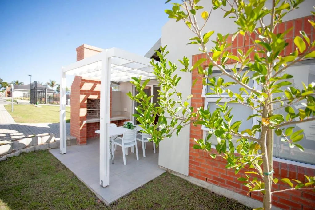 Modern white pergola with seating area and young plants on grass