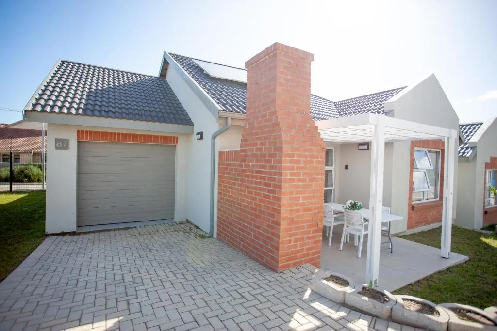 Modern townhouse with garage, patio, and brick chimney facade