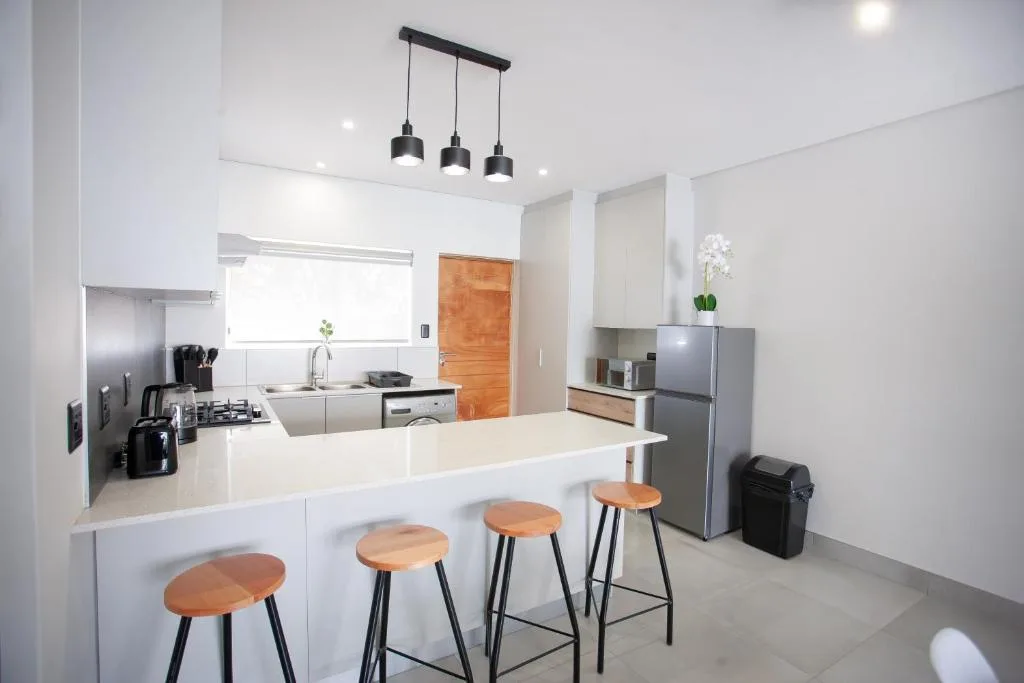 Modern kitchen with white cabinetry, island seating, and pendant lights