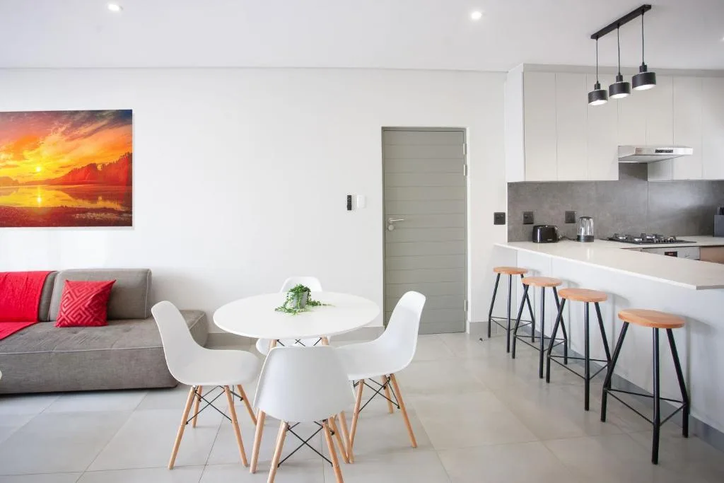 Modern lounge with grey sofa, dining table, and open-plan kitchen area