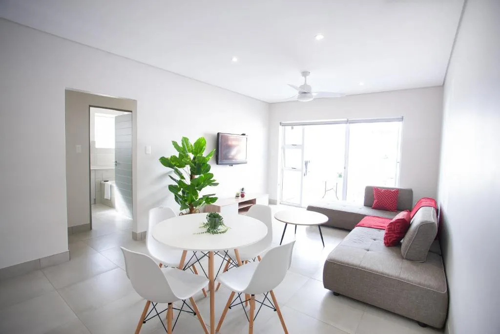 Modern lounge with gray sofa, pink cushions, dining table, and potted plant