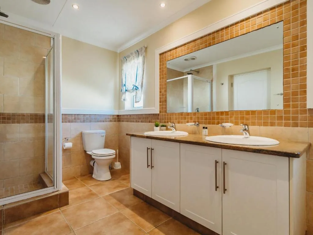 Modern bathroom with double vanity, large mirror, and spacious shower enclosure