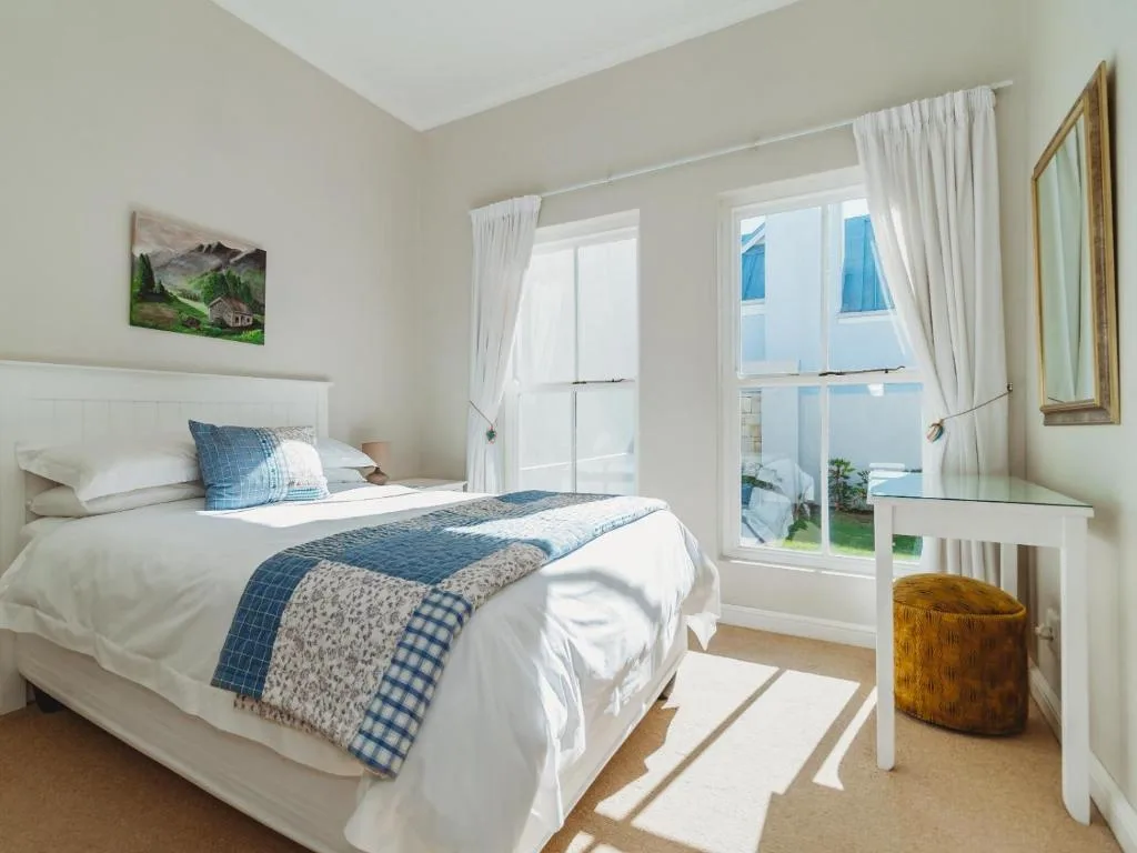 Bright bedroom with white bed, blue bedding, ocean view through glass doors