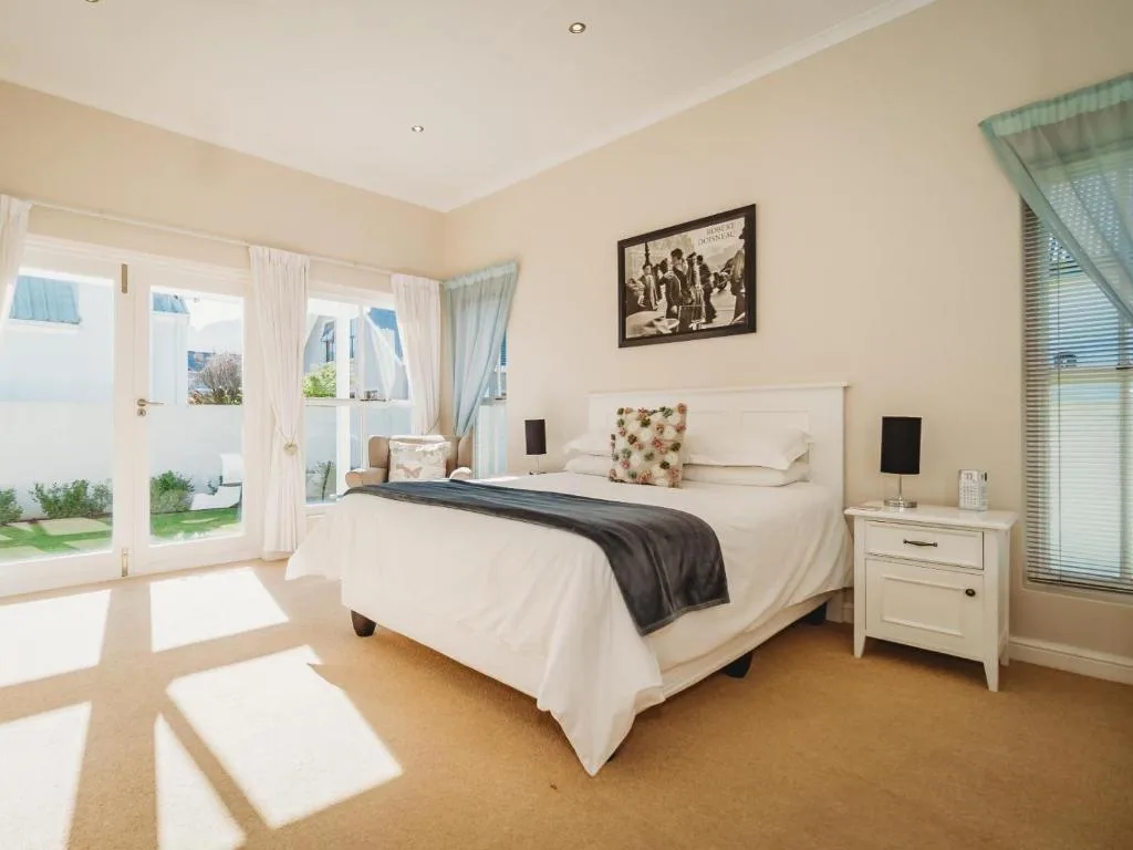 Bright bedroom with queen bed, white bedding, and garden access doors
