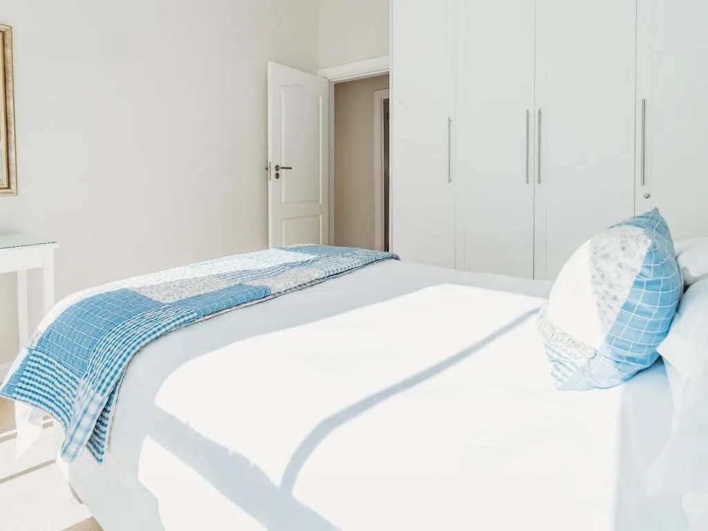Bright bedroom with white bed, blue bedding, and built-in wardrobes
