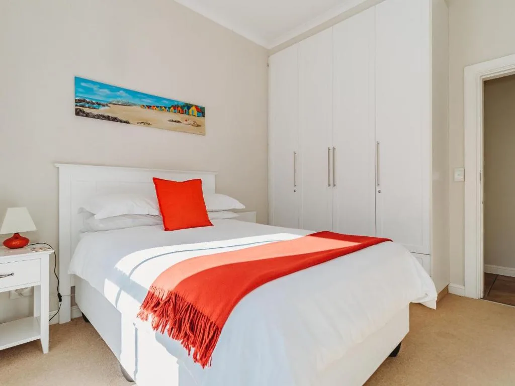 Bright bedroom with white bed, red accents, and built-in wardrobes