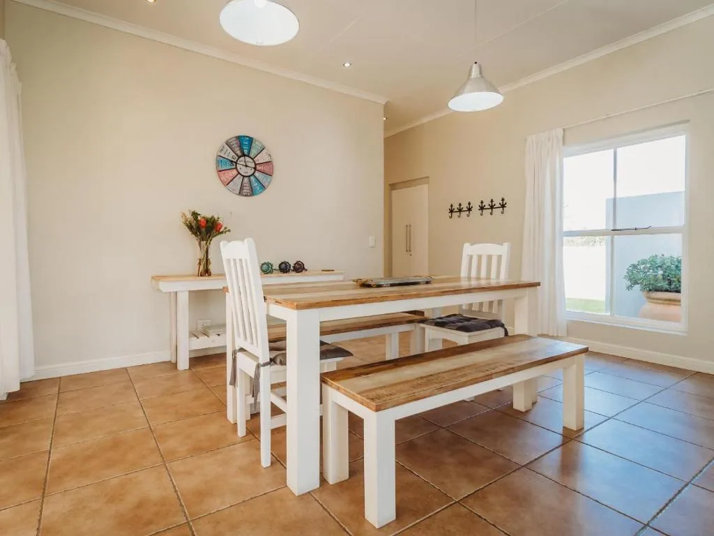 Bright dining room with wooden table, bench seating, and ocean views through windows