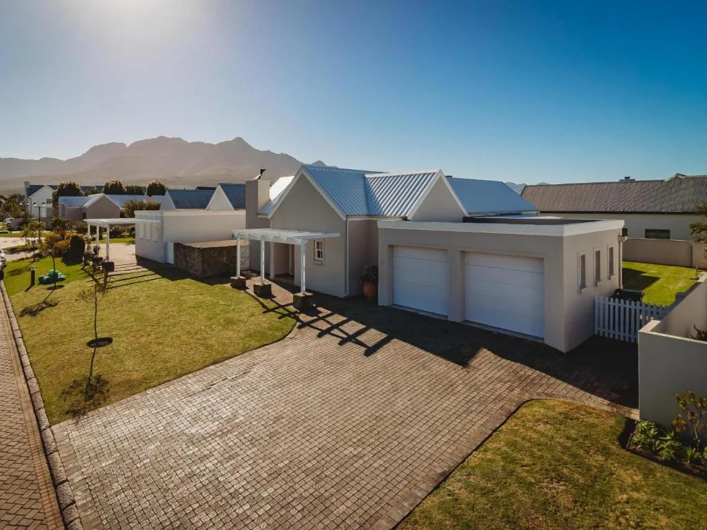 Modern white cottage with double garage and manicured garden, mountain backdrop