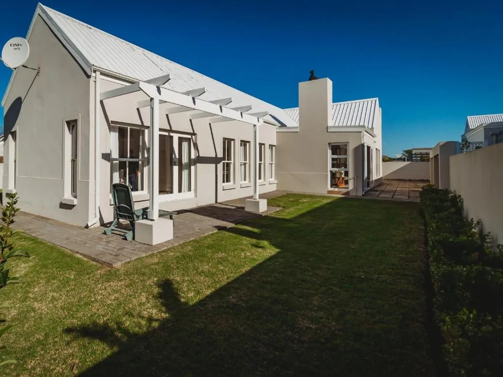 Modern white cottage with metal roof and pergola-covered patio area