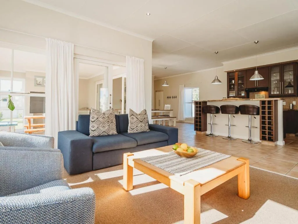 Open-plan lounge with blue sofa, armchairs, and wooden coffee table