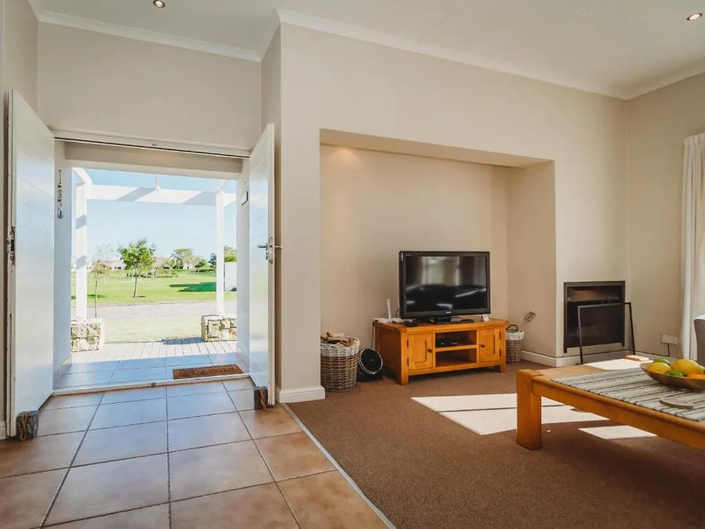 Spacious living room with TV, wooden furniture, and garden view through open doors