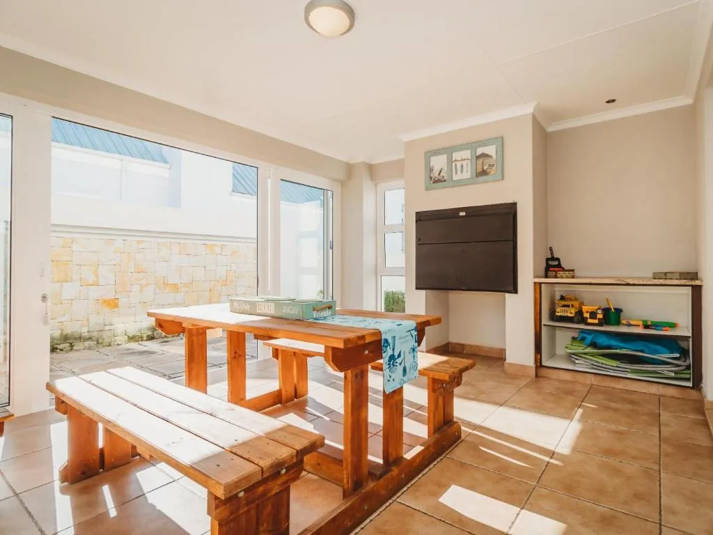 Open-plan lounge with wooden table, TV, and outdoor access to patio