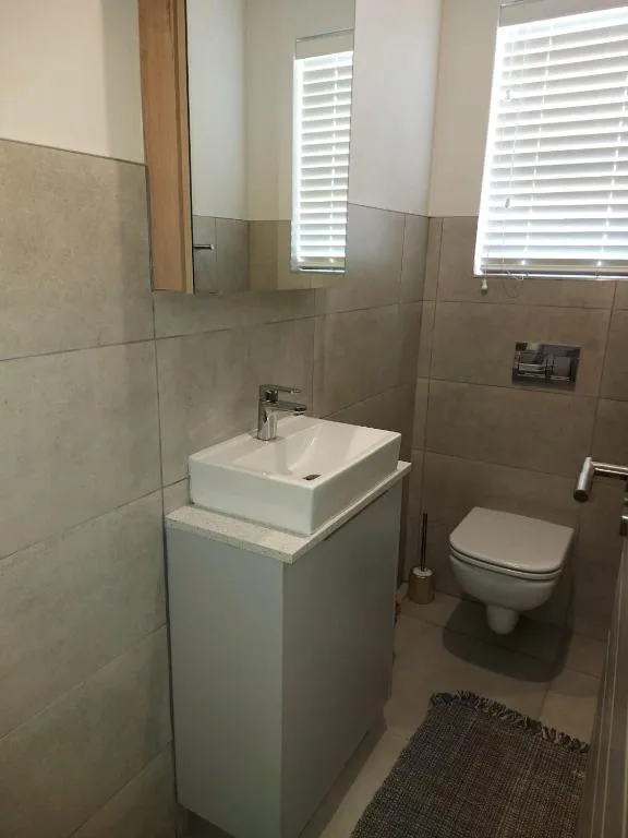 Modern bathroom with white vessel sink, toilet, and tiled walls
