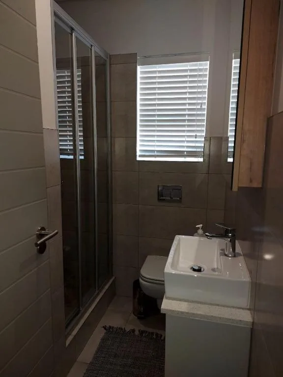 Modern bathroom with shower enclosure, white sink, and toilet