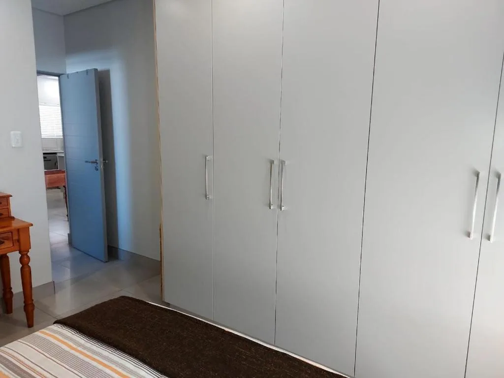 Modern bedroom with large built-in white wardrobe and polished concrete floors