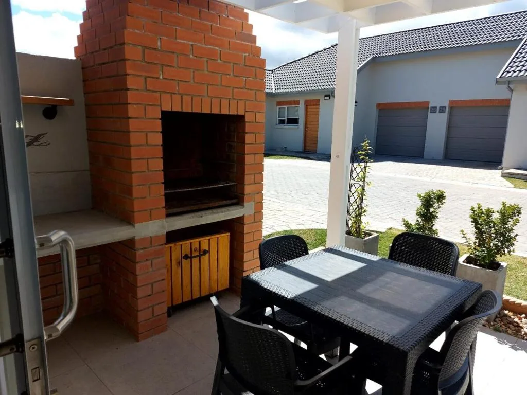 Covered patio with dining table, built-in brick braai, and garden views