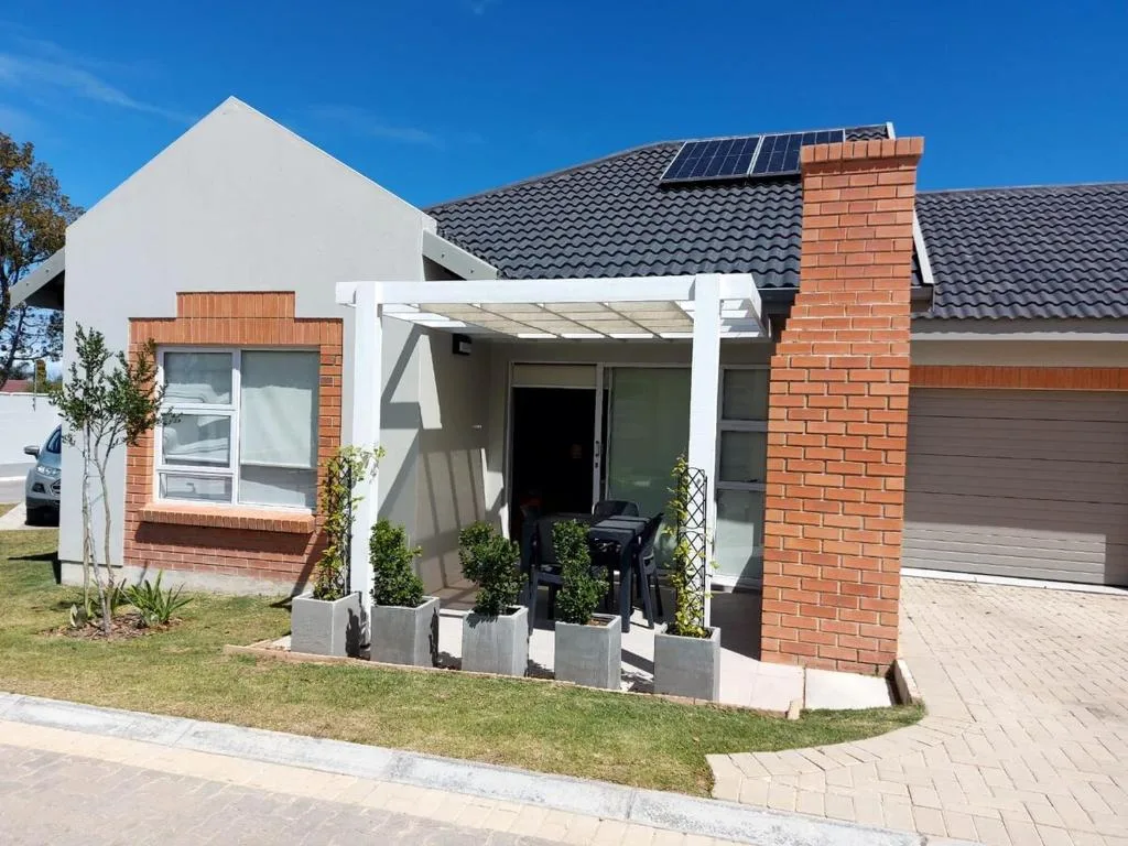 Modern white and brick holiday home with pergola entrance and manicured gardens