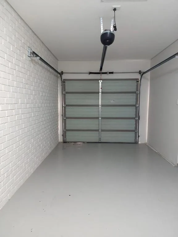 Empty garage interior with white brick walls and glass panel door