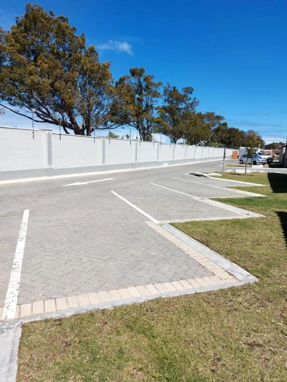 Driveway and parking area with white fence and mature trees
