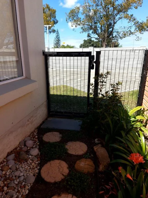 Gated garden entrance with stepping stones and flowering plants outdoors