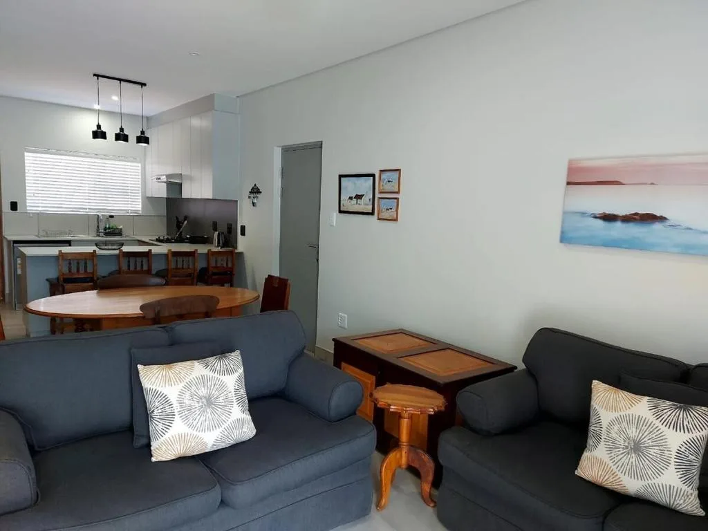 Open-plan lounge with blue sofas and decorative pillows overlooking kitchen area