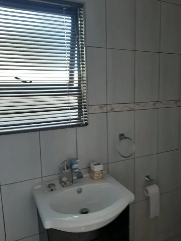 Bathroom vanity with white sink and horizontal blinds window