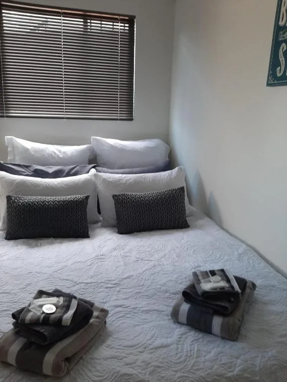 Neat bedroom with white bedding, black pillows, and neatly folded towels