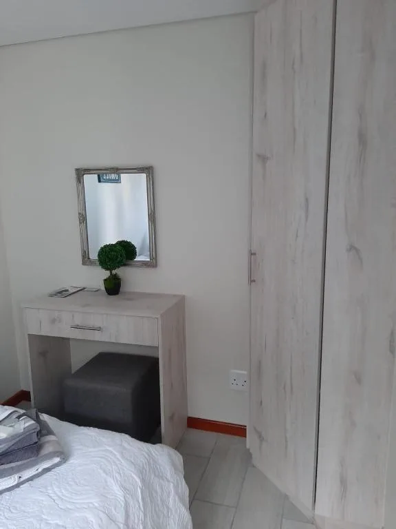 Bright bedroom corner with vanity desk, mirror, and potted plant