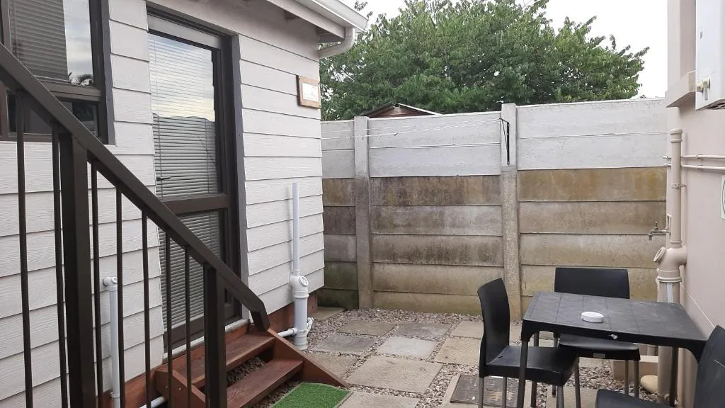 Outdoor patio area with black dining table and chairs, bordered by concrete walls