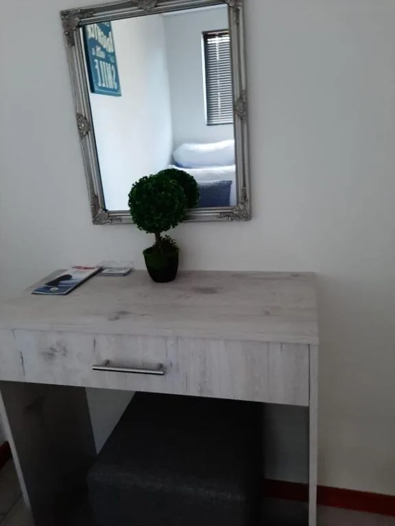 Vanity desk with mirror, potted plant, and contemporary styling