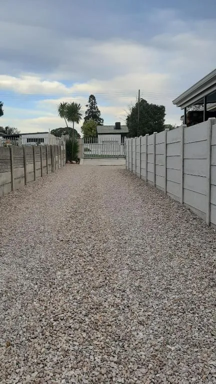 Gravel driveway with white boundary fences and property entrance gates