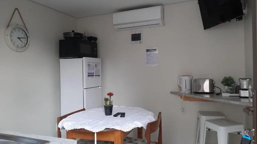 Compact kitchen with white fridge, kettle, and dining table