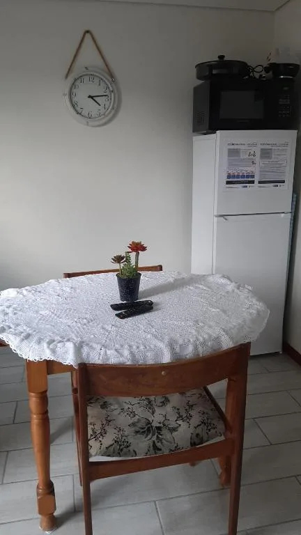 Kitchen corner with white fridge, round wooden table, wall clock