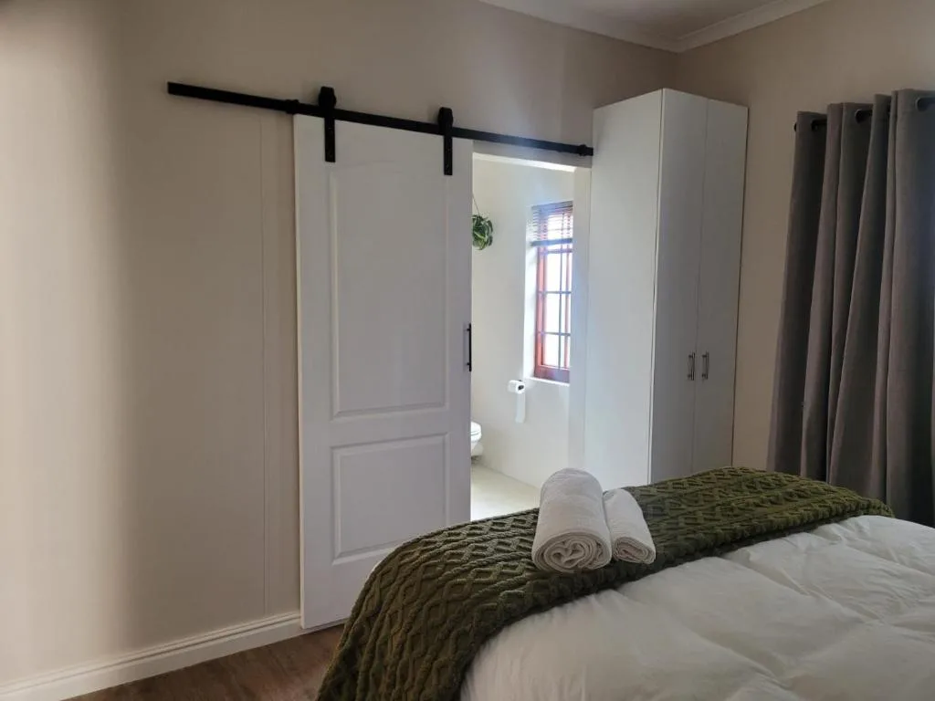 Modern bedroom with white bed, rolled towels, barn door, ensuite bathroom access