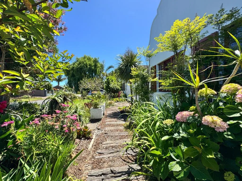 Lush garden pathway with flowering plants leading to modern white building