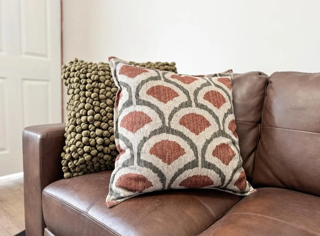 Brown leather sofa with decorative patterned pillows and textured cushions