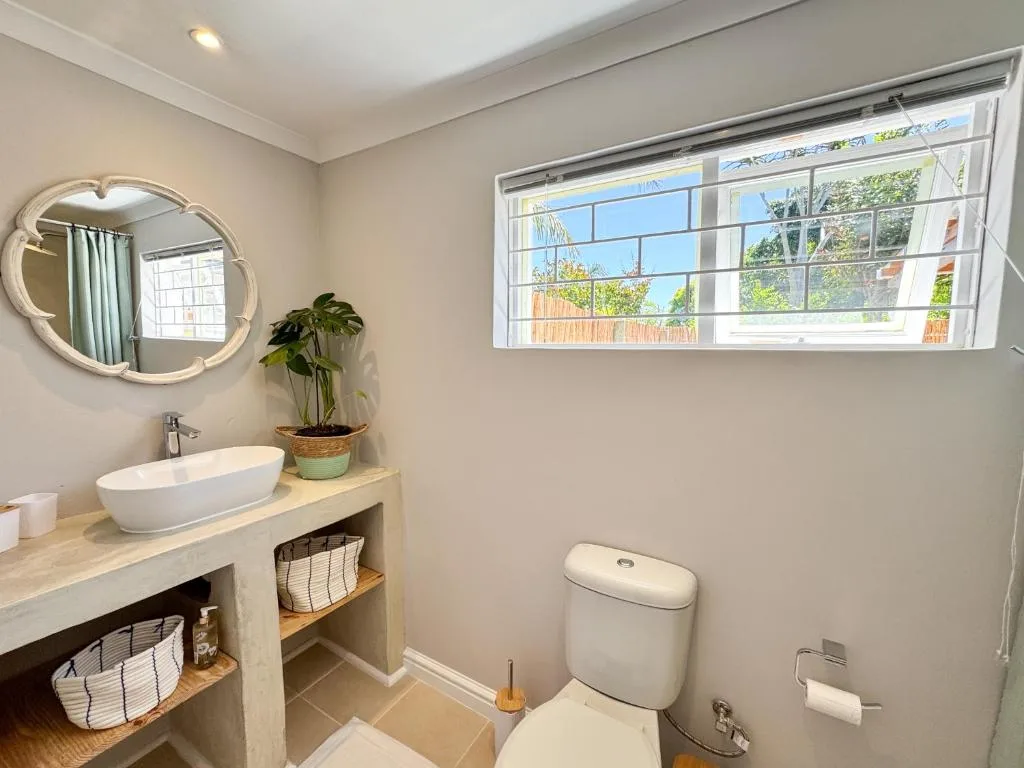 Bright bathroom with vessel sink, toilet, and garden views through window